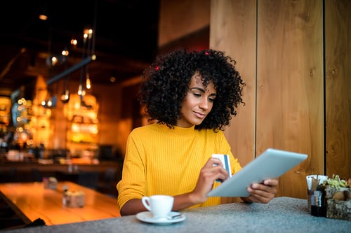 woman at coffeeshop shopping online with her tablet woman at coffeeshop shopping online with her tablet holding a credit card