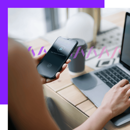 How Network-Powered APIs Are Changing the Game header Photoillustration of a woman holding a cell phone in her left hand with a lock and badge icon on it to indicate security; with her right hand, she types on a Mac laptop