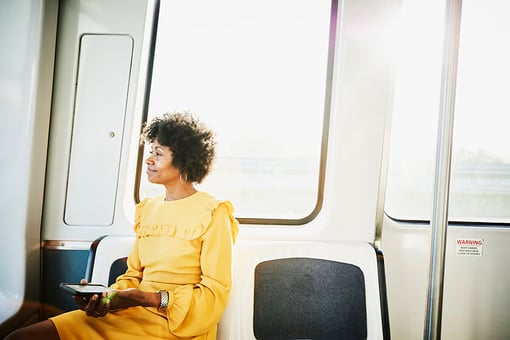 woman sitting on public transportation holding phone woman sitting on public transportation holding phone