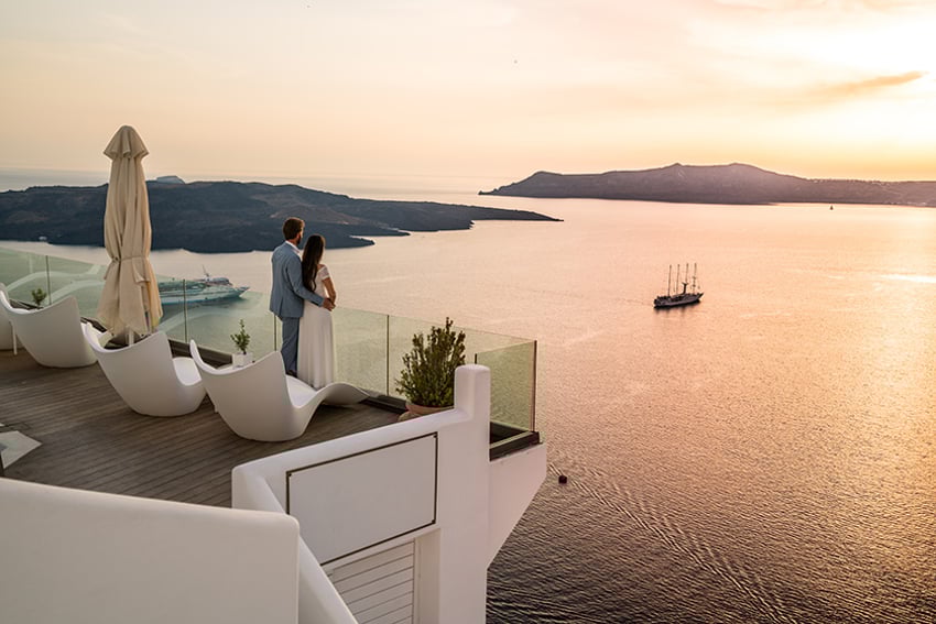 Couple Standing on Terrace Luxury hotel in Greece overlooking the caldera of greek island santorini terrace with seaview vacation honeymoon